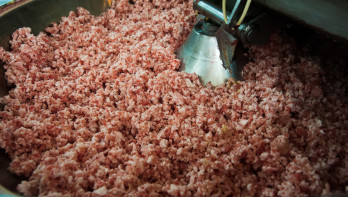 Productielijn voor worst, waarbij ingrediënten worden gemengd tijdens het industriële productieproces.