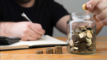 Man stopt munten in een potje en noteert iets in een kasboek