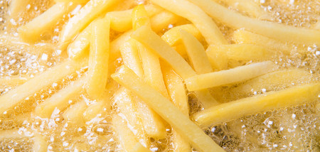 Verse aardappelfrites worden goudbruin gefrituurd in hete olie