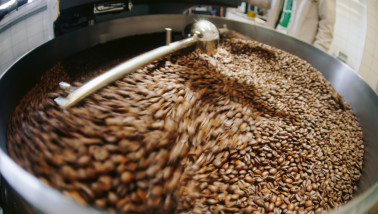 Koffiebonen die worden geroosterd in een industriële koffiebrander.