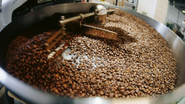 Koffiebonen die worden geroosterd in een industriële koffiebrander.