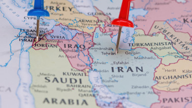 Israël gemarkeerd met een blauwe punaise en Iran met een rode punaise op een politieke wereldkaart.