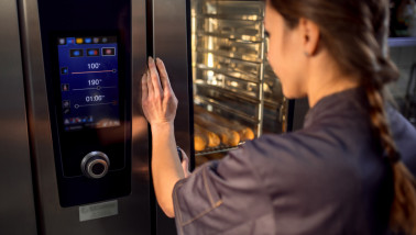 Medewerker in bakkerij haalt brood uit de oven